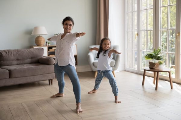 Mum and daughter doing yoga together, symbolising balance, wellbeing, and passing down positive financial habits