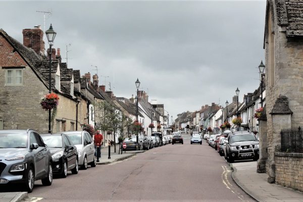 Cricklade High Street on a sunny day, lined with independent shops, historic buildings, and local businesses.