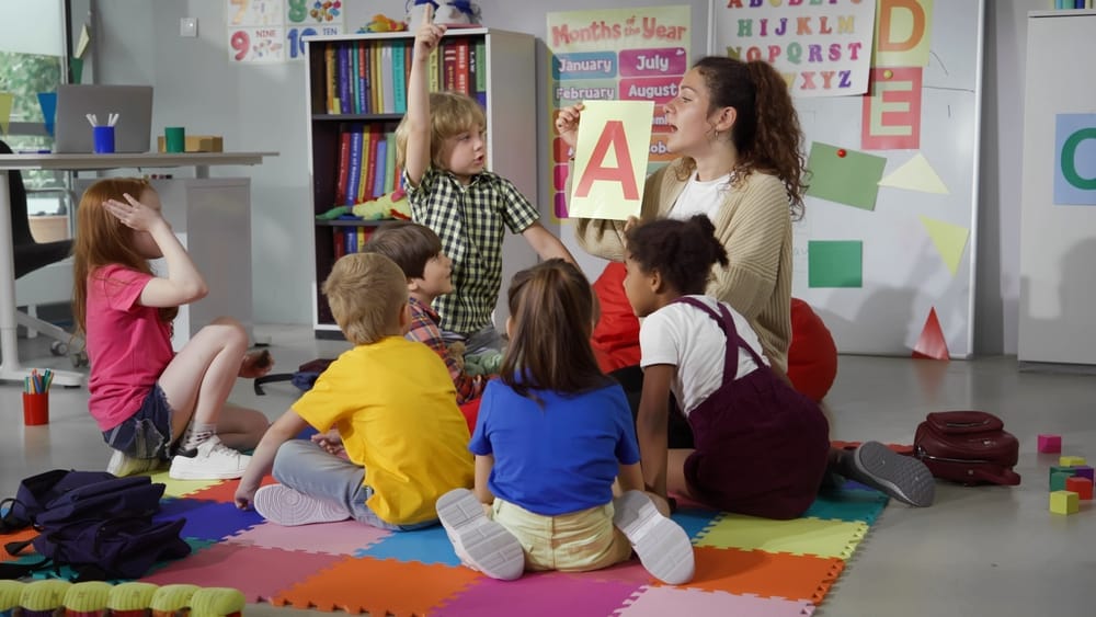Teacher supporting young children in classroom – childcare funding changes September 2025 Teacher with small children in a nursery setting, representing the expansion of free childcare funding in September 2025
