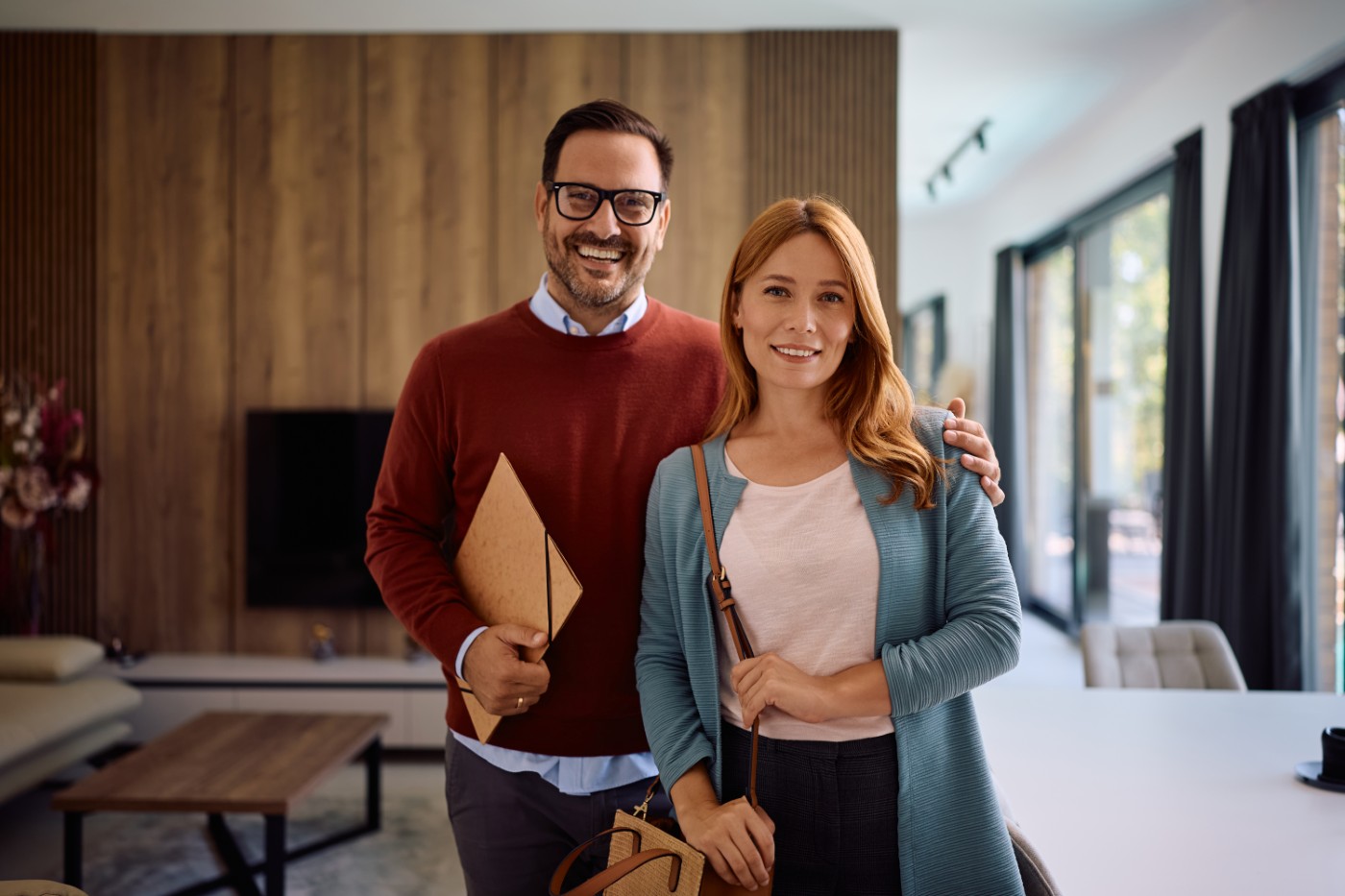 Portrait of happy new homeowners looking at camera. Happy couple standing int he living room of their new house and looking at camera.
