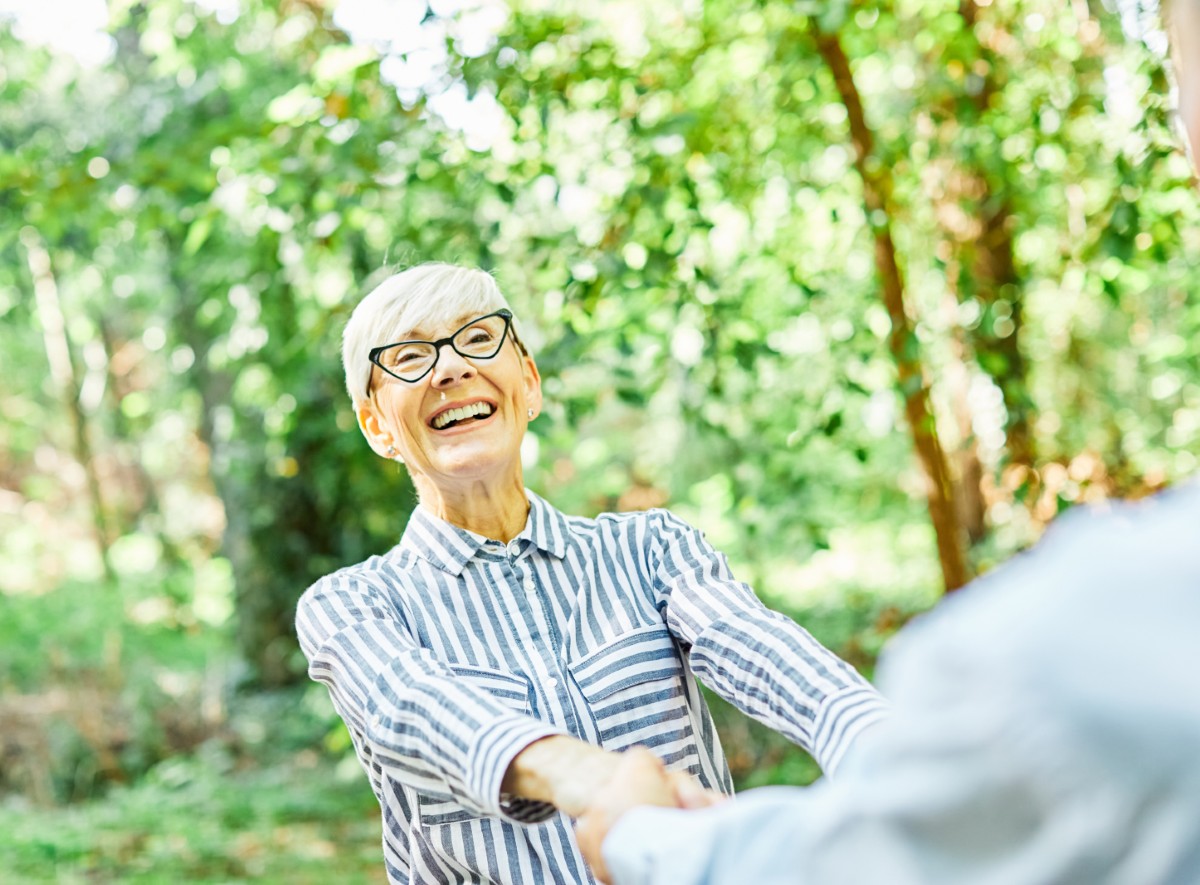 woman man senior couple happy retirement together elderly freedo Happy active senior couple, portrait of an elderly woman with her husband dancing or swinging and holding hands in park outdoors